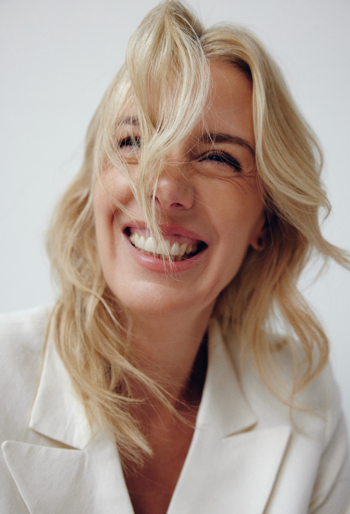 Woman with blonde hair blowing in the wind against a white background