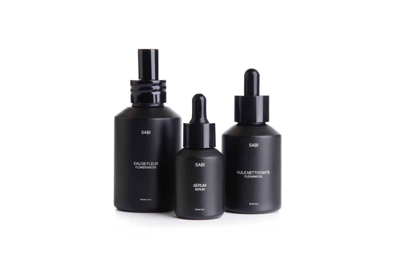 Three black skincare bottles with droppers on a white background
