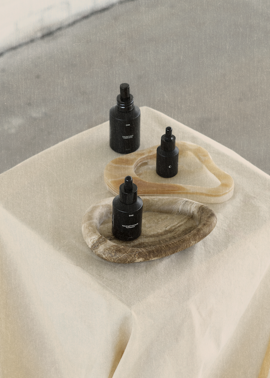 Three black dropper bottles on a stone surface with a neutral background